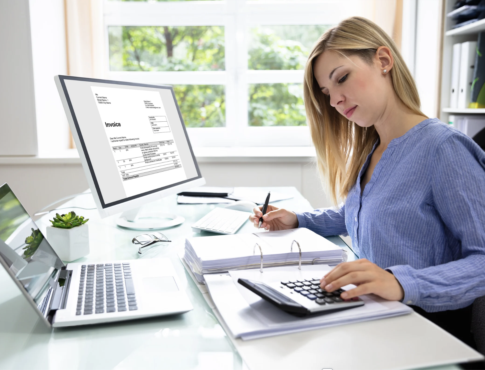 Accounting professional working at desk with calculator, documents, and computer