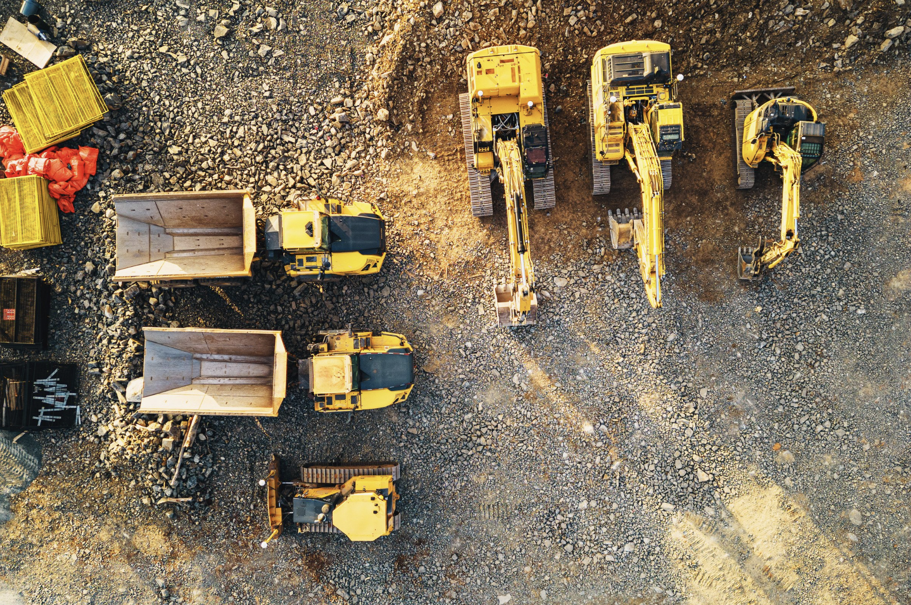Aerial view of several pieces of yellow construction equipment lined up on dirt ground